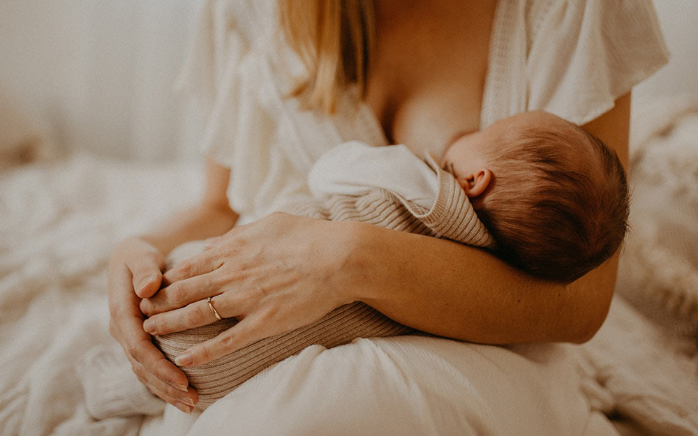 Mama hält ihr Neugeborenes im Arm und still es.