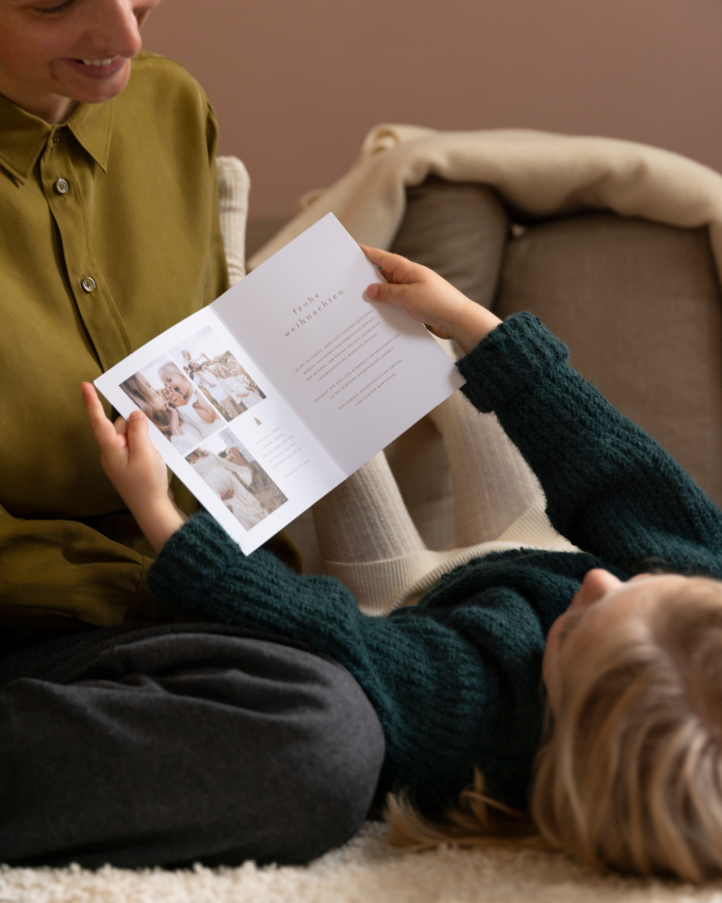 Kleines Mädchen mit Mutter beim Betrachten einer Weihnachtskarte auf der Couch