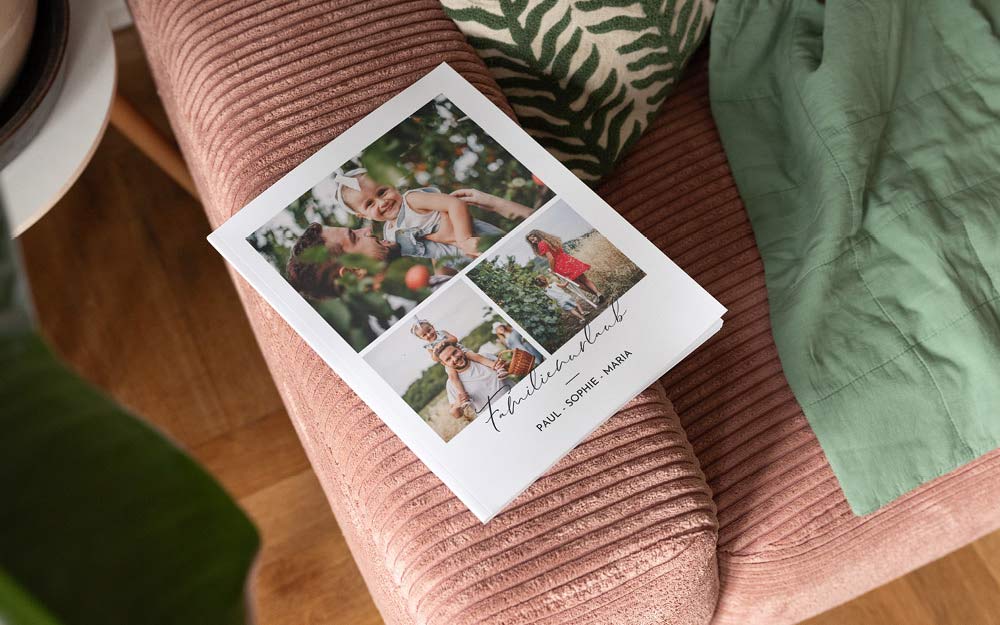 Fotobuch über einen Familenurlaub liegt auf einer Couch