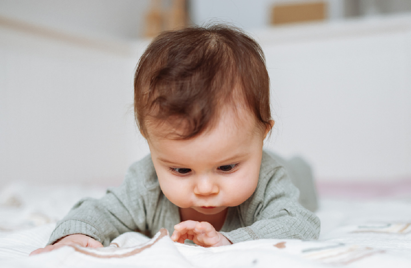 Baby liegt auf dem Bauch und betrachtet seine Hand