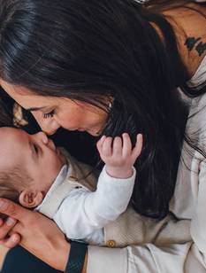 Baby auf dem Arm der Mutter greift nach Zeigefinder des Vaters