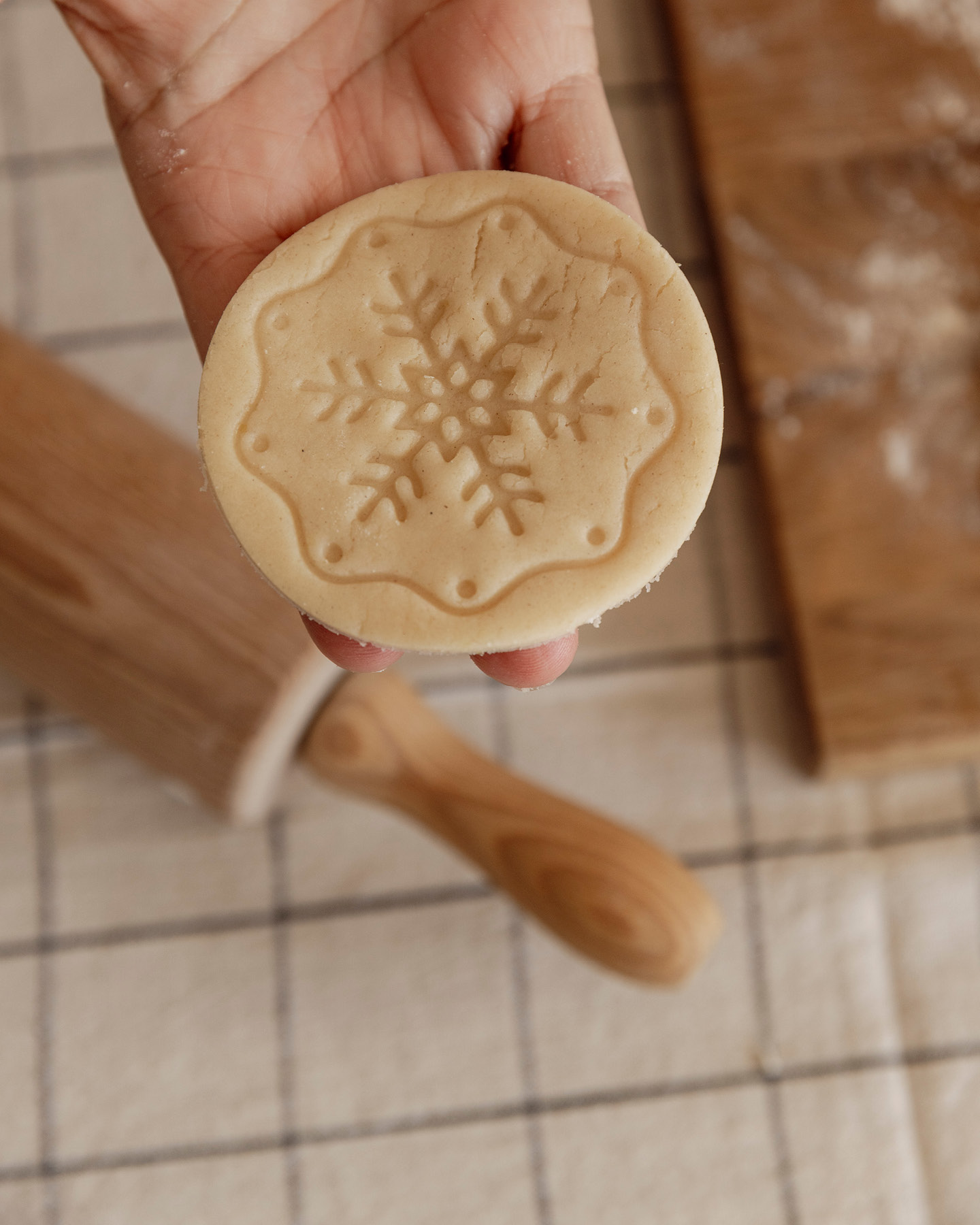 Rund ausgestochener Keksteig, bestempelt mit weihnachtlichem Schneeflockenmotiv