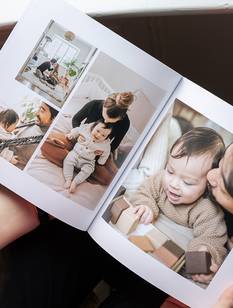 Frau (nicht im Bild) blättert in einem Fotobuch mit Babybildern